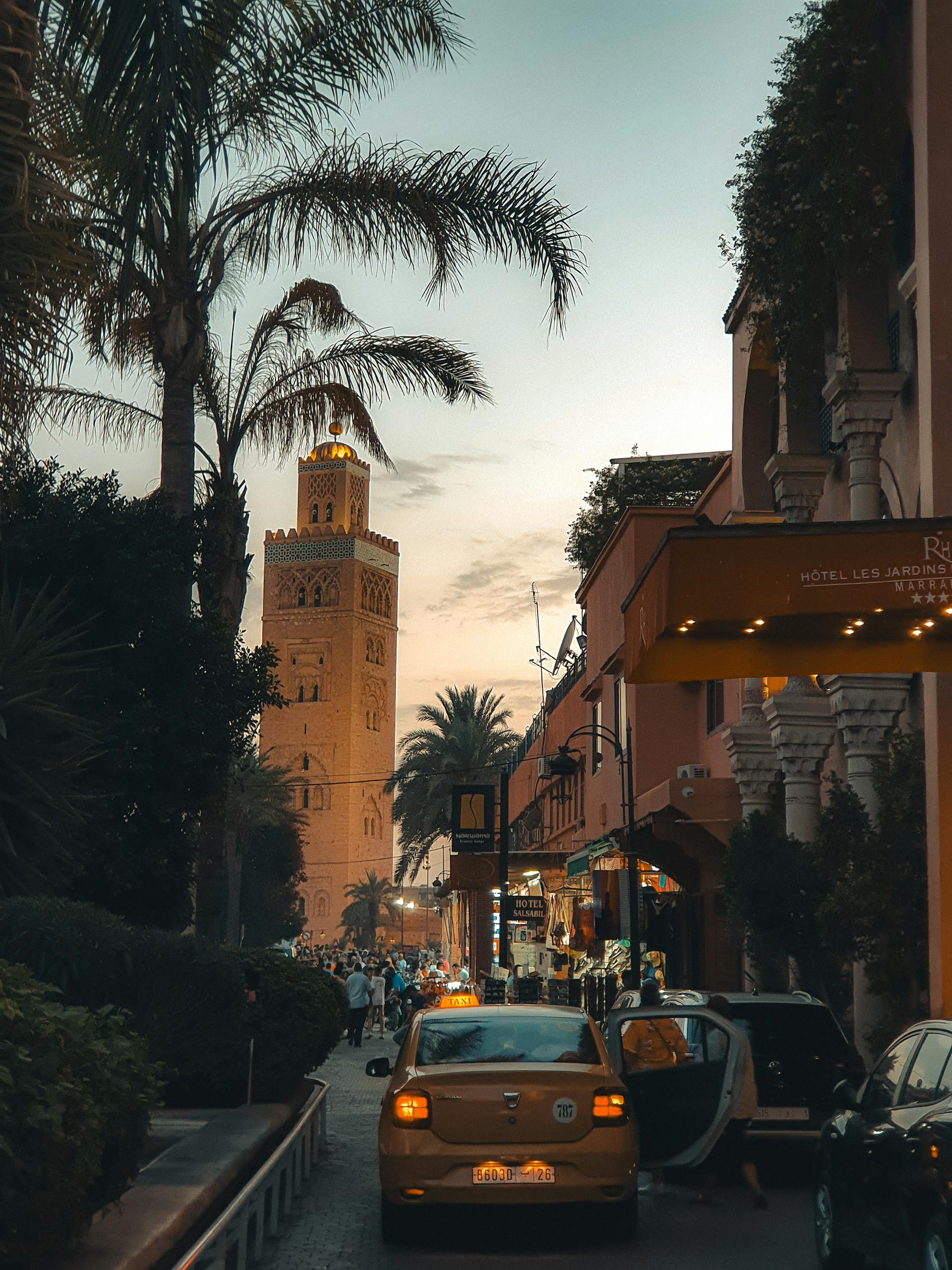 Explore the vibrant Marrakech streets at sunset, featuring iconic minaret and lively atmosphere.
